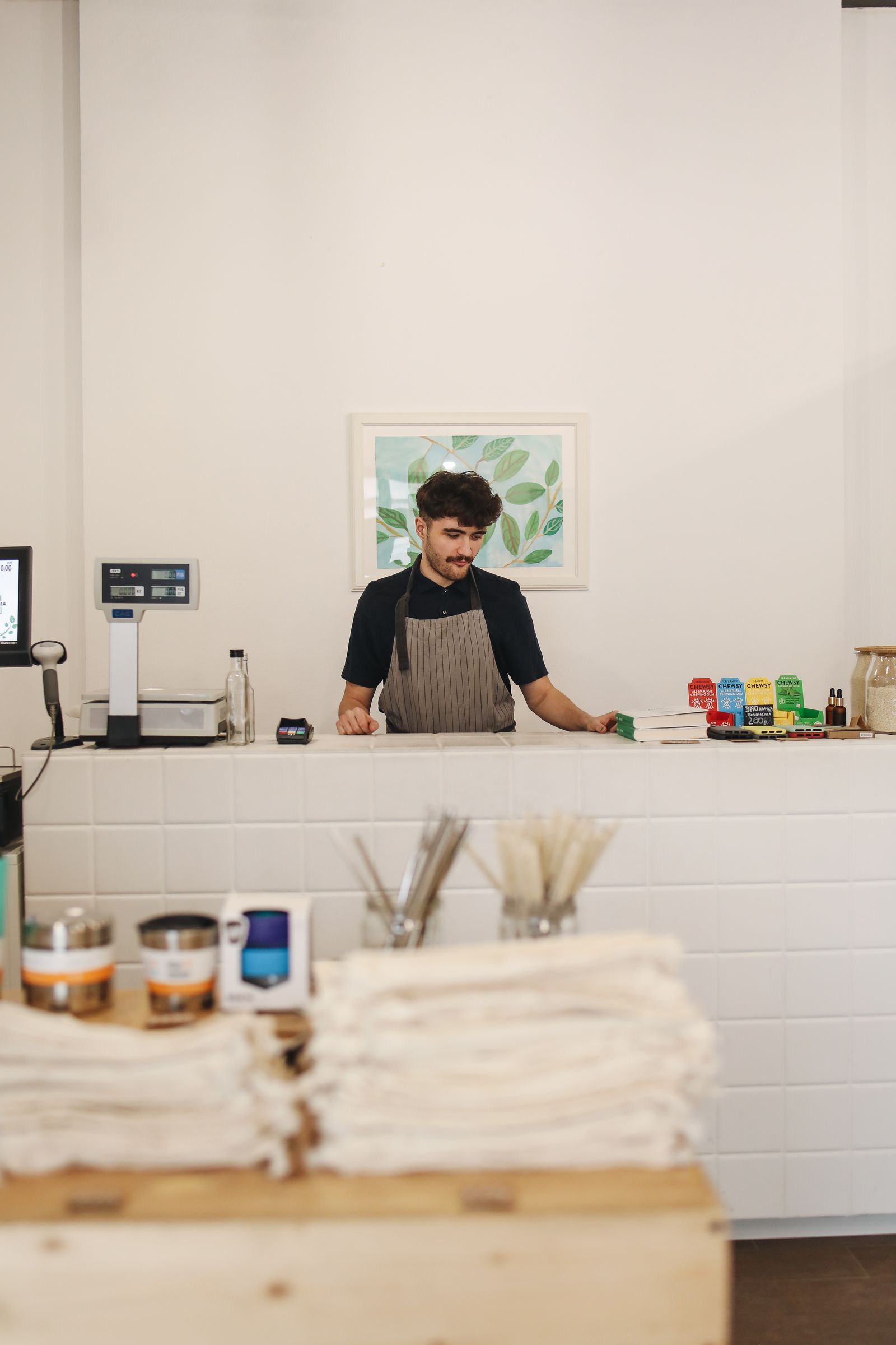 Small shop owner in an apron standing behind the counter